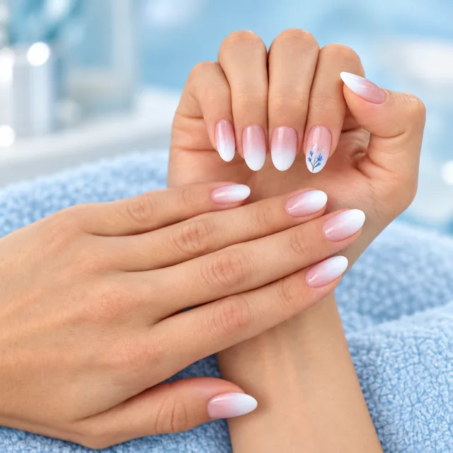 Pink and white ombre French nails with a blue floral accent